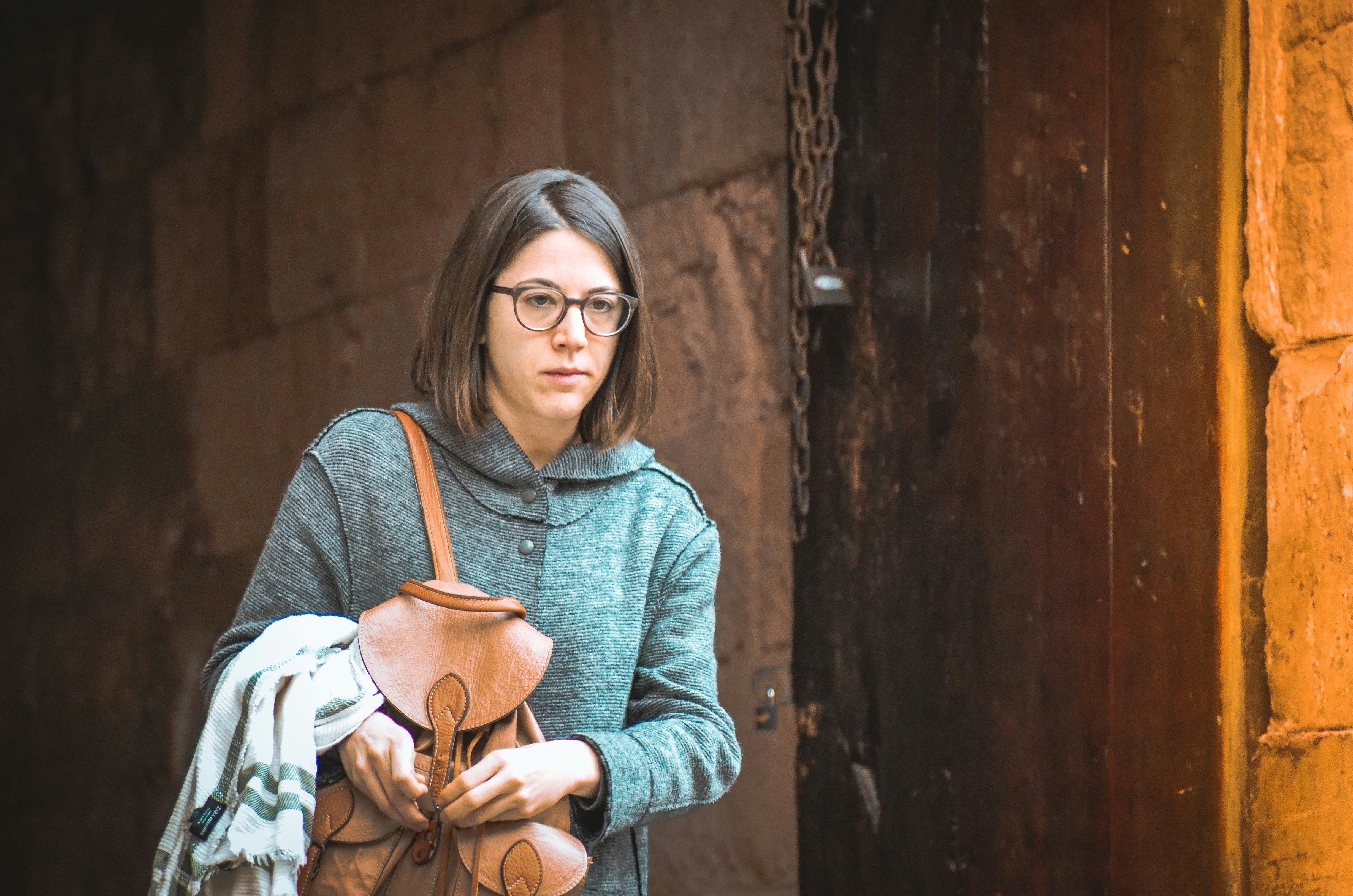 woman walking beside brown wooden door during daytime